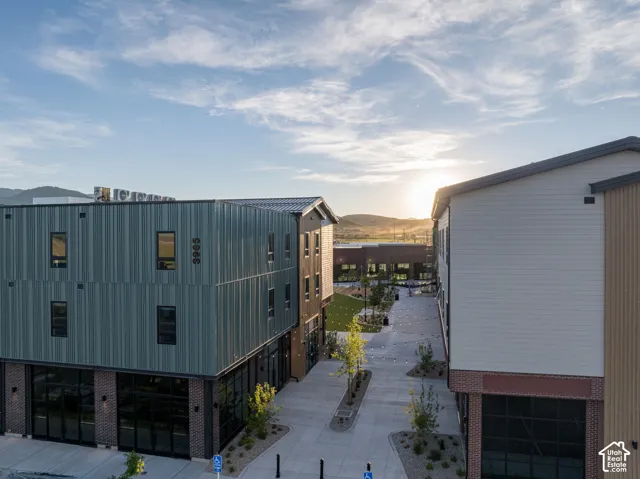 Multi-story structure with vertical metal siding, masonry brick base, horizontal lap siding, and paved pedestrian promenade