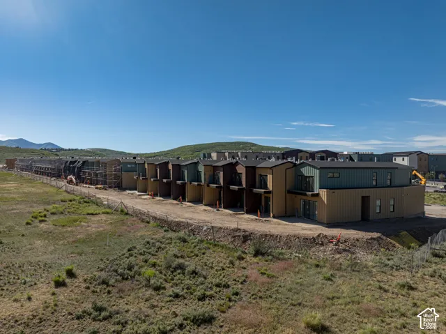Multi-family residential complex featuring vertical metal siding, neutral-toned exteriors, pitched roofing, and prominent mountain backdrop