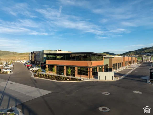 Commercial complex featuring red brick masonry, expansive storefront glass, metal panel siding, flat roofline, and paved parking area