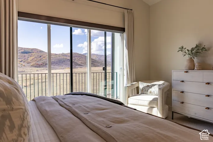 Floor-to-ceiling glass sliding doors, metal balcony railing, and mountain backdrop