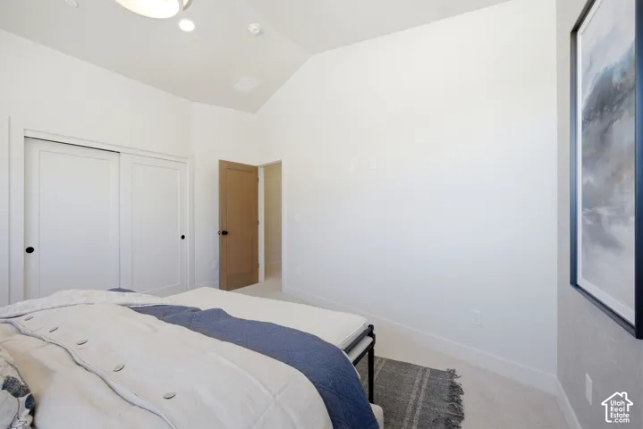 Vaulted ceilings, sliding panel closet doors, neutral carpeting, and a solid-core wood-finish interior door featuring matte black hardware