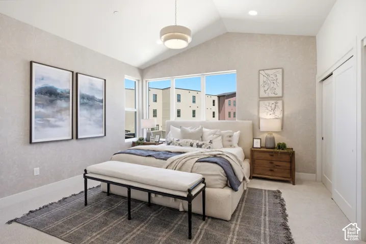 Vaulted ceiling with a central pendant light fixture, expansive windows, textured wall surfacing, and neutral carpeting
