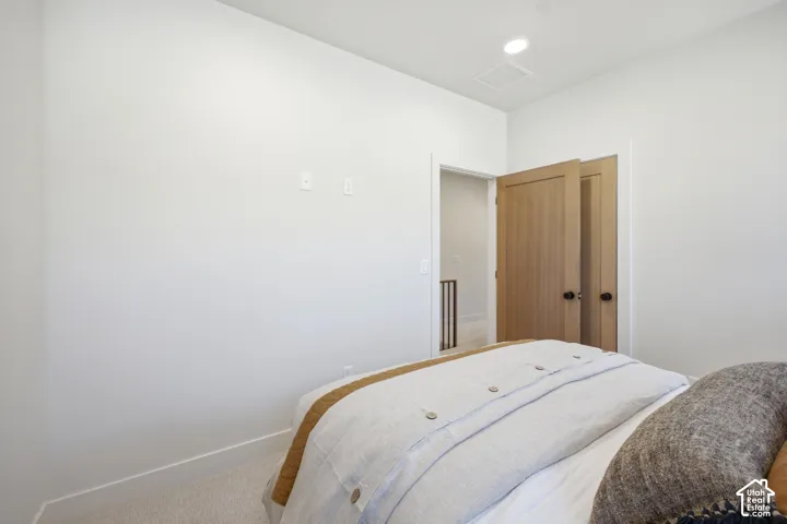 Neutral-toned interior featuring recessed lighting, light-toned carpeted flooring, and wood-finish doors with matte black hardware