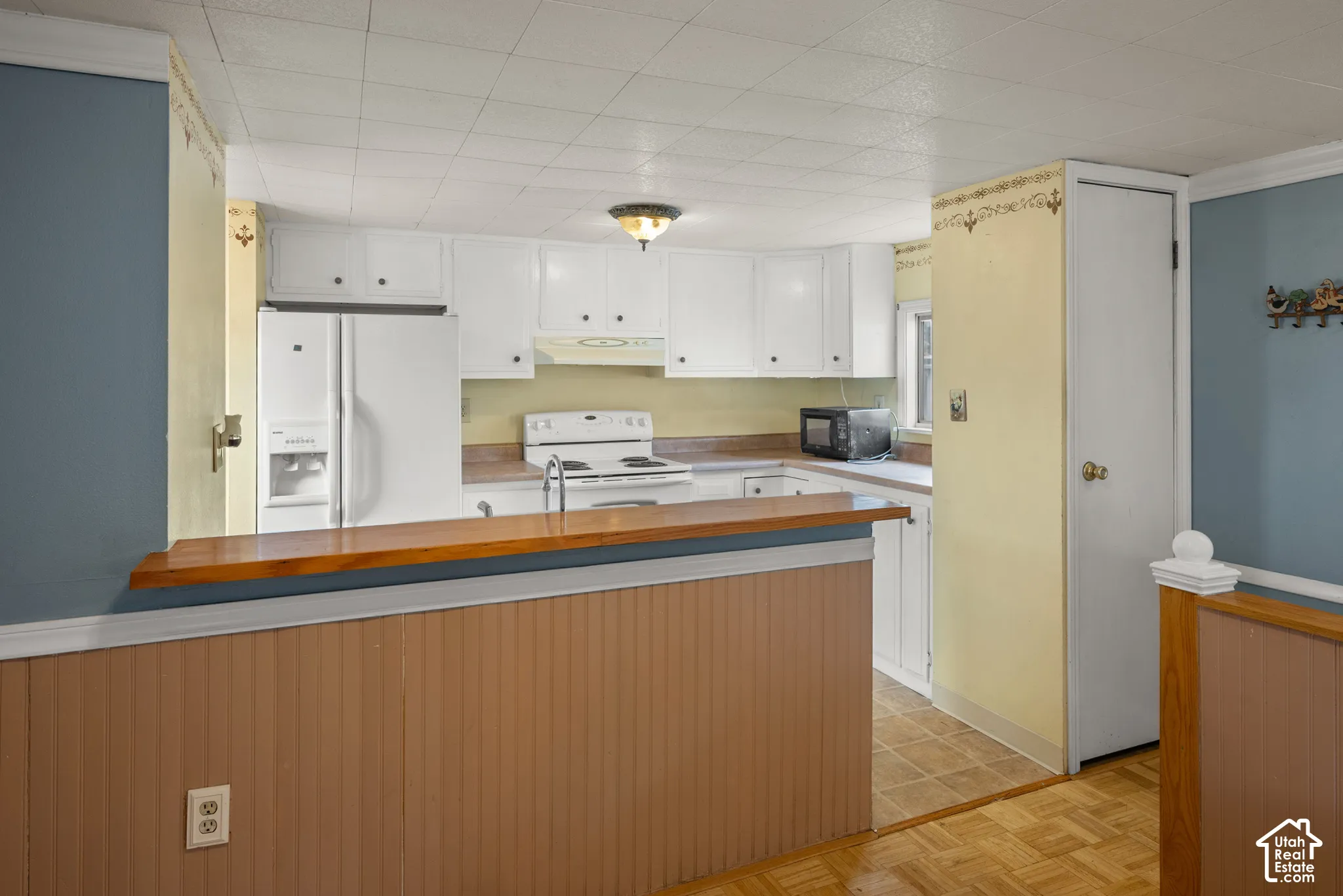 Kitchen featuring white cabinetry, a wood-topped breakfast bar, built-in pantry, and parquet flooring
