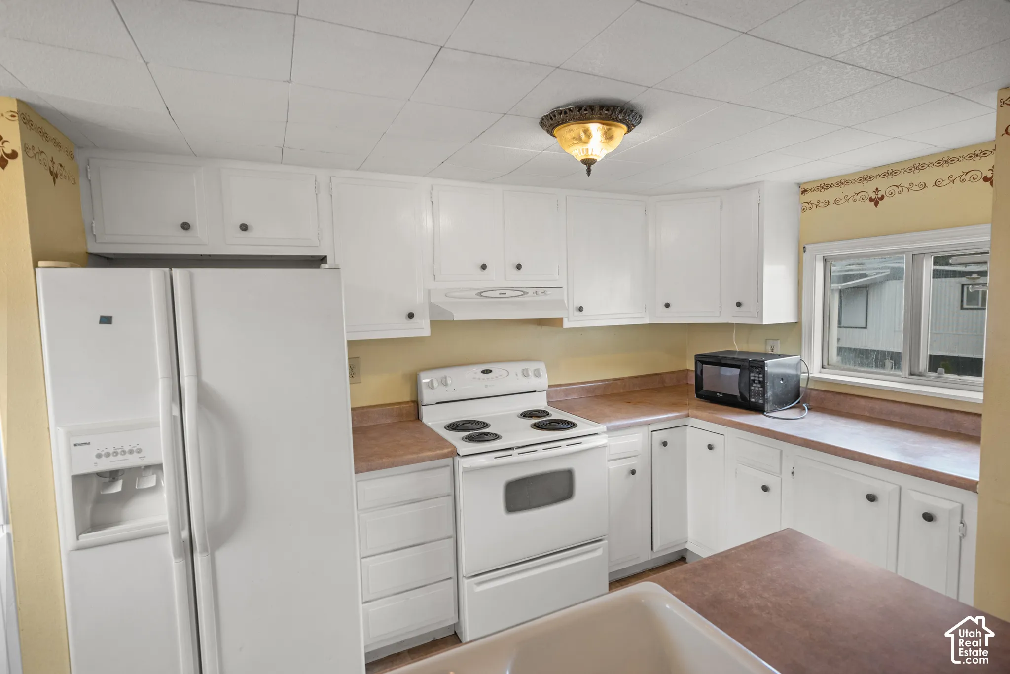 Kitchen featuring white cabinetry, integrated range, hood, and window with natural light exposure