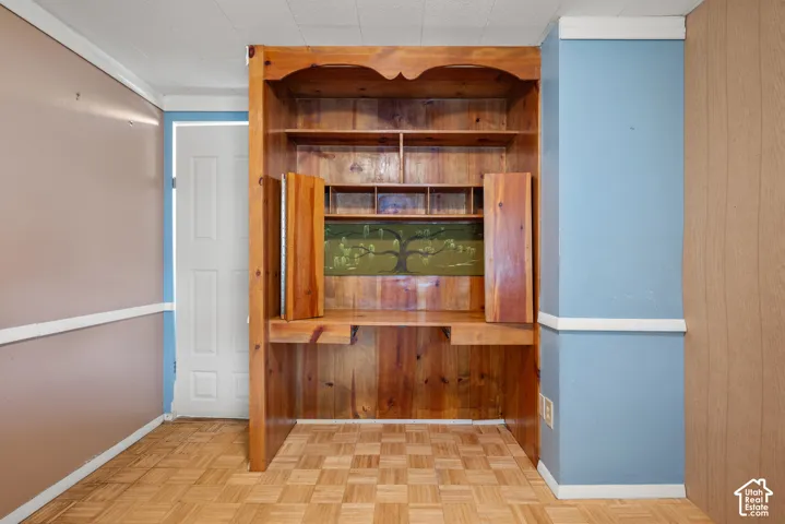 Built-in wood cabinetry featuring an integrated desk, open shelving, and compartmentalized storage, complemented by parquet wood-finish flooring and a white paneled door
