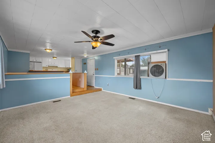 Open-concept interior featuring a multi-level floor plan, ceiling fan with integrated lighting, wood-finish stair treads, and panelled wall detailing