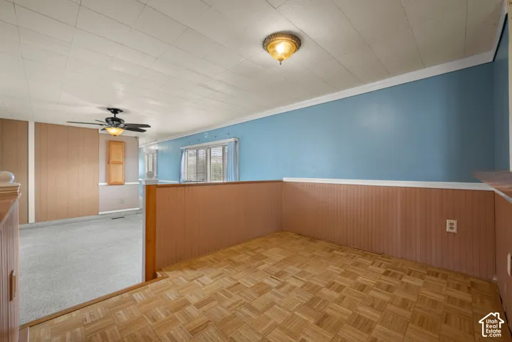 Parquet wood-finish flooring, wood-paneled wainscoting, flush-mount lighting, ceiling fan, and multi-paned windows