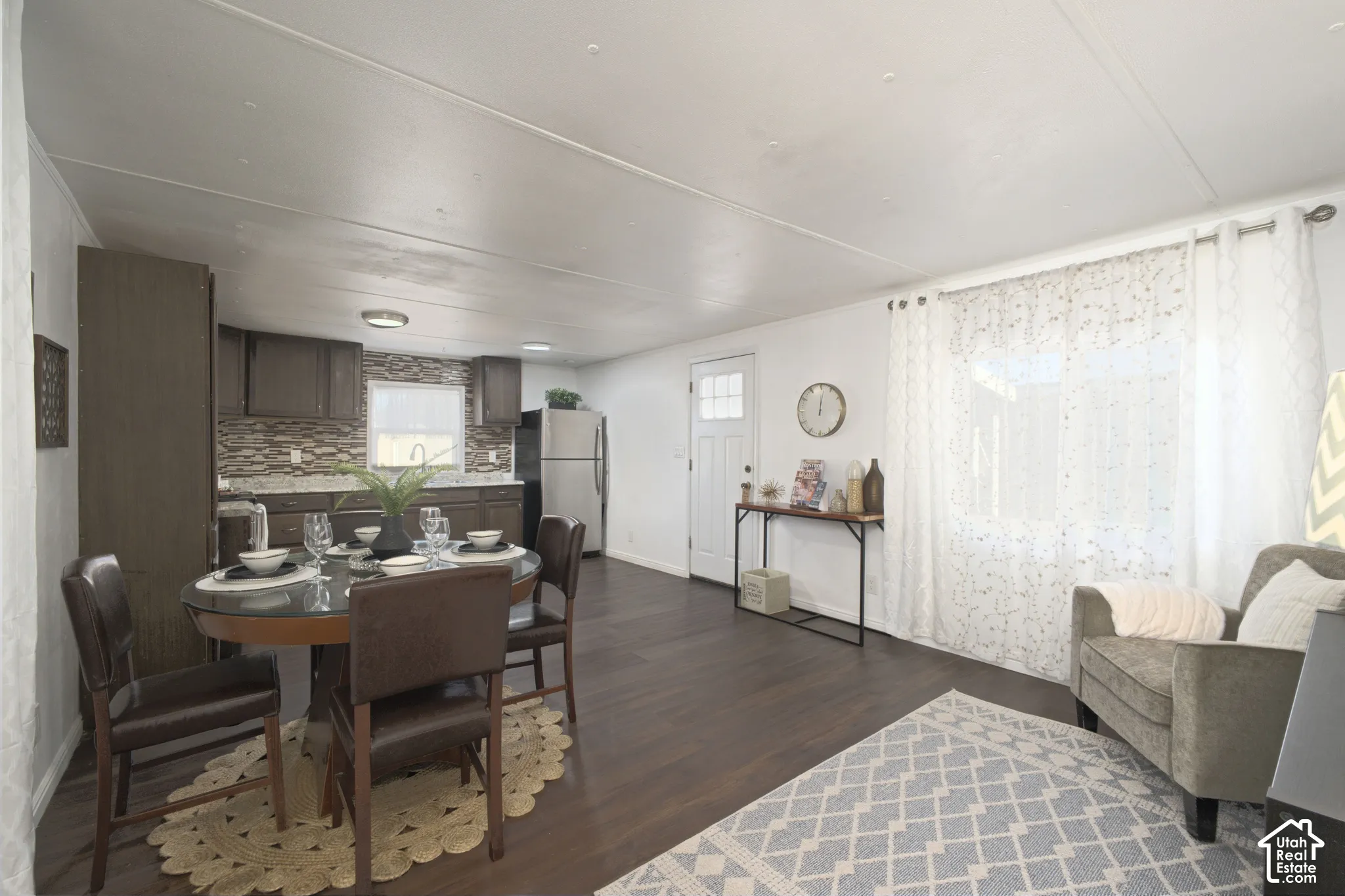 Dark wood-finish flooring, cabinetry with stone-finish countertops, tiled backsplash, and a multi-lite exterior entry door