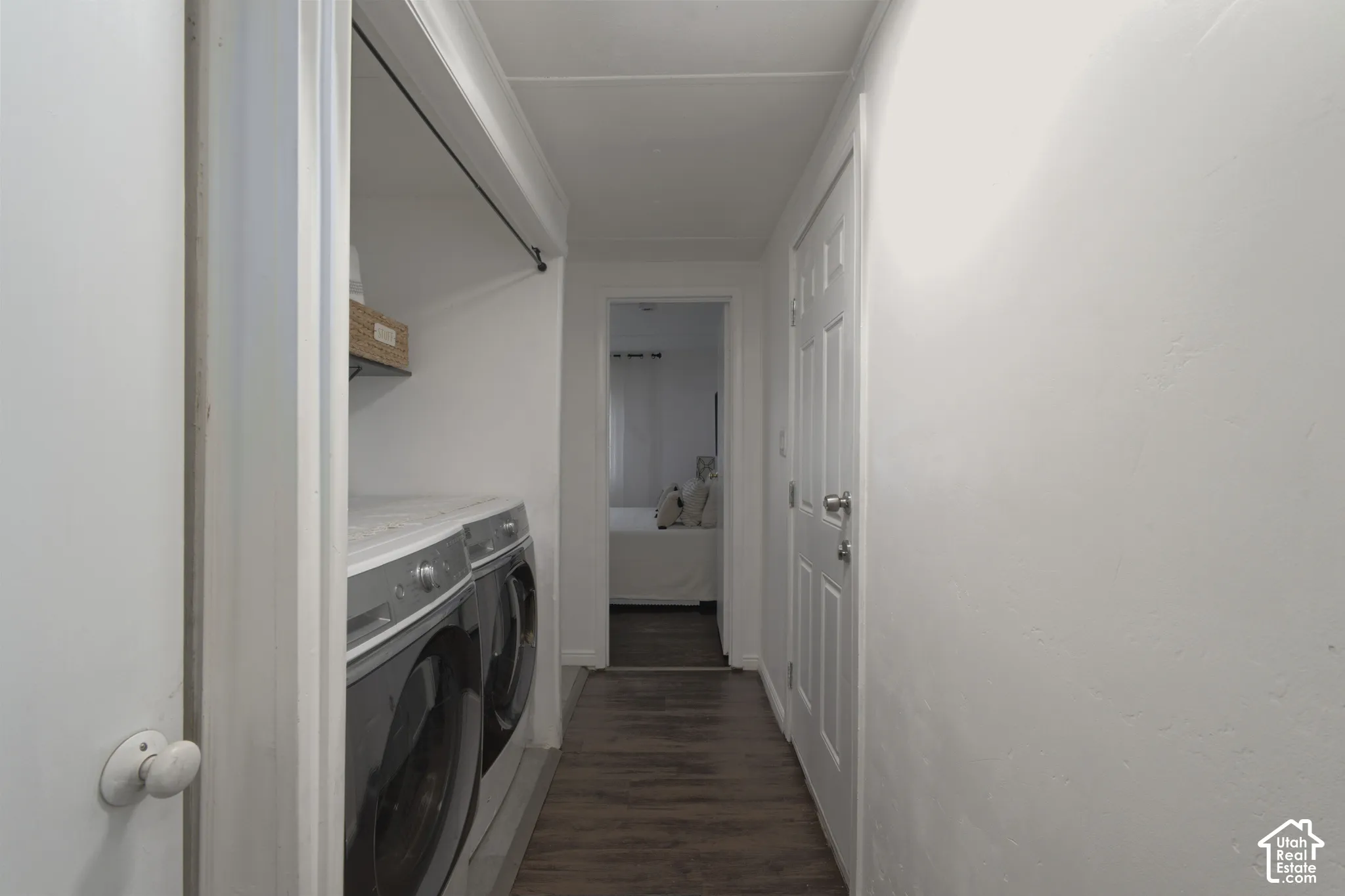 Laundry area featuring wood-finish flooring, white paneled interior doors, and a built-in closet rod
