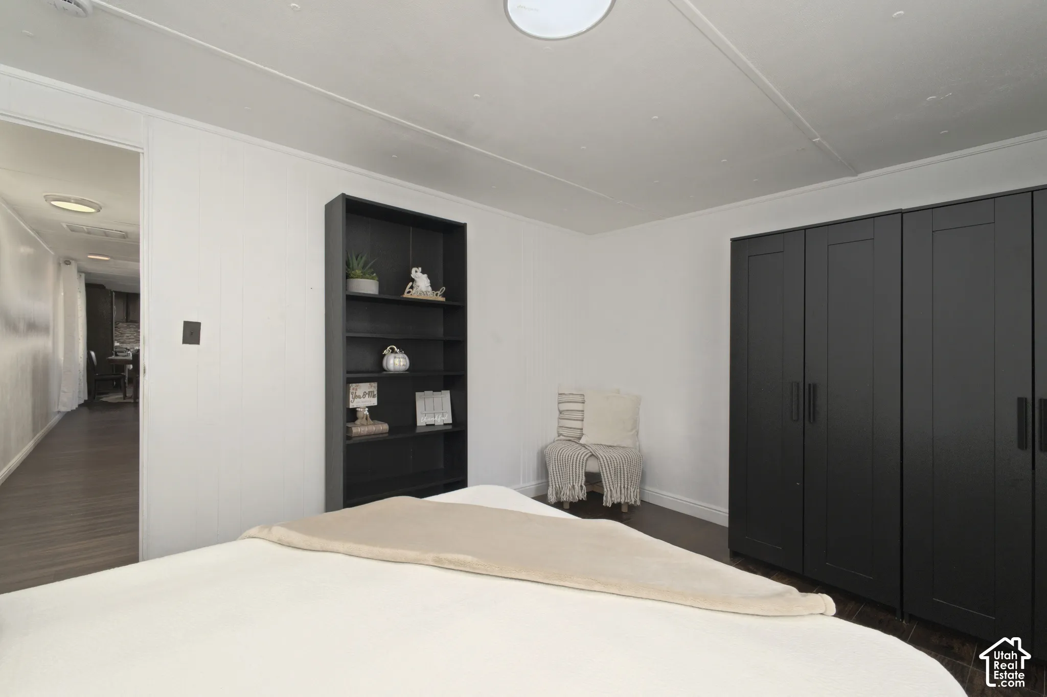 Room featuring dark wood-finish flooring, built-in shelving, and a dark matte-finish wardrobe