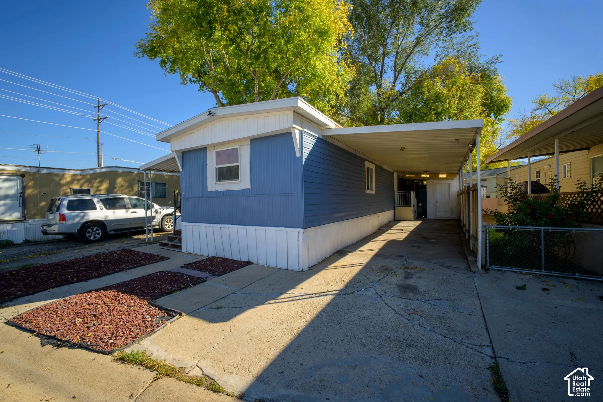 Blue siding exterior featuring a concrete driveway, attached covered carport, and ornamental gravel landscaping