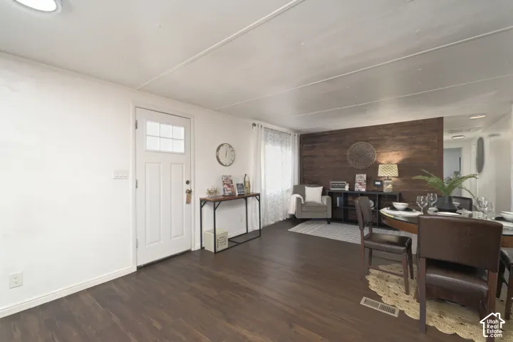 Wood-finish flooring, dark wood-tone accent wall, and multi-panel exterior entry door with glass pane