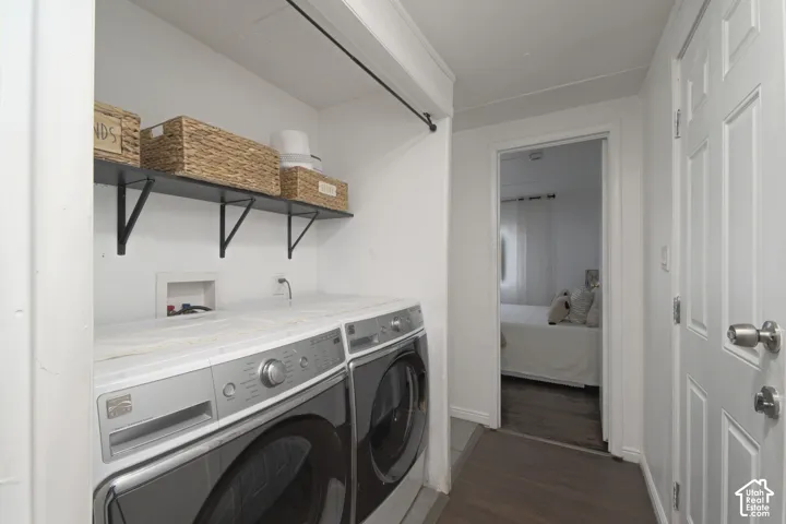 Laundry space featuring wall-mounted black shelving, a dedicated clothing rod, and wood-finish flooring