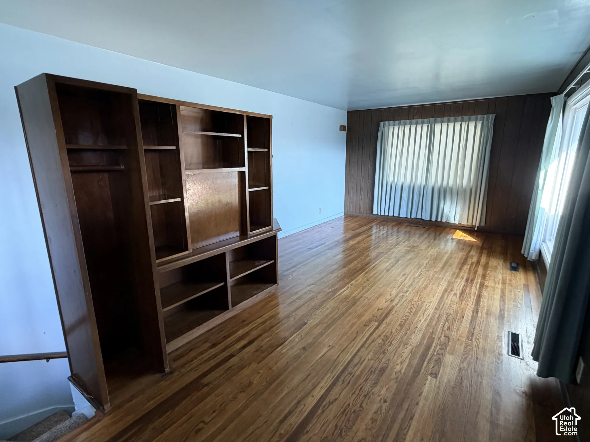 Wood-finish flooring, built-in wooden shelving unit, and wood-paneled accent wall