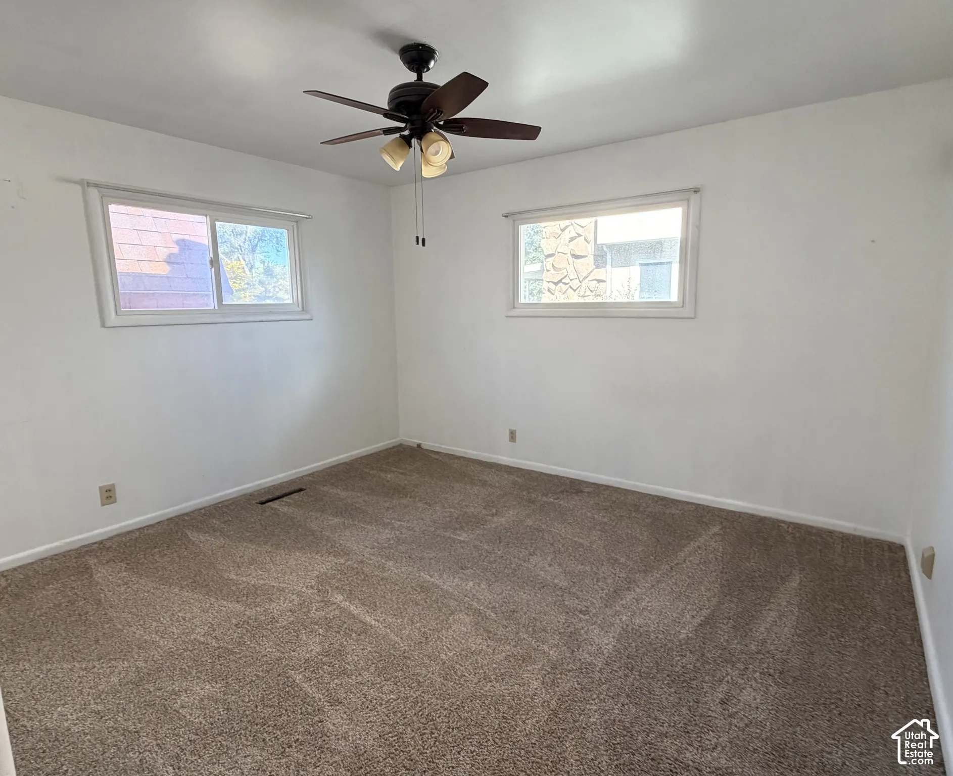 Room featuring neutral wall-to-wall carpeting, two horizontal sliding windows, and a ceiling-mounted light fixture with a fan