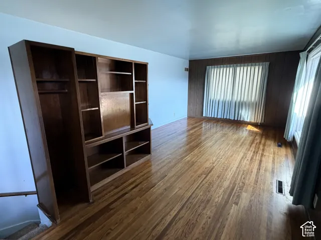 Wood-finish flooring, built-in wooden shelving unit, and wood-paneled accent wall