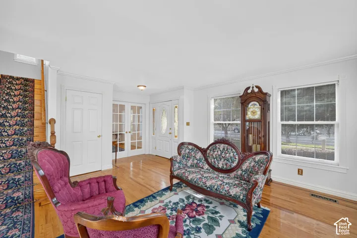 Entryway featuring wood-finish flooring, multi-pane glass French doors, crown molding, and dual windows