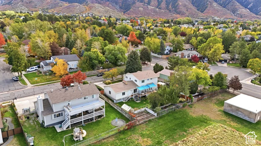 Aerial perspective featuring multi-level residential structures, expansive green space, mature canopy trees, and a mountain backdrop