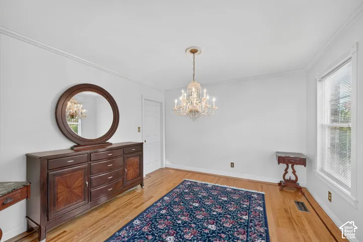 Hardwood flooring, crown molding, and a multi-tiered crystal chandelier