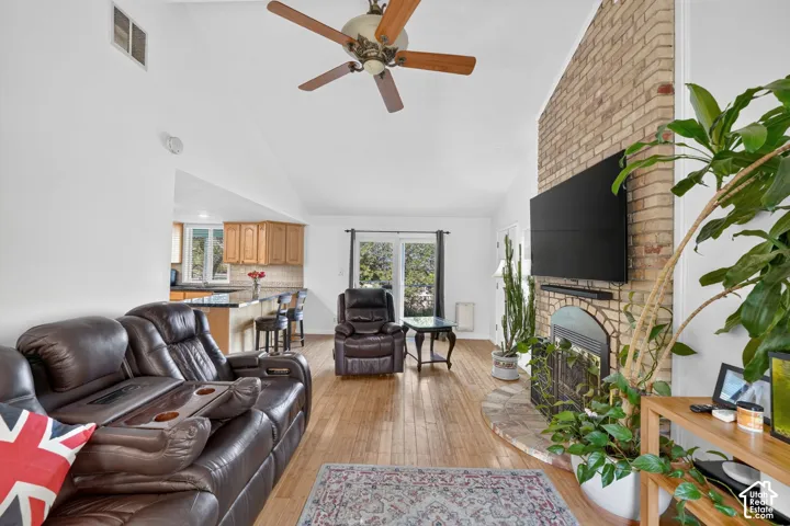Vaulted ceilings, wood-finish flooring, floor-to-ceiling brick fireplace, and glass patio doors
