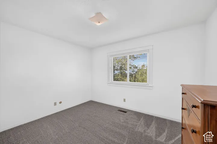 Neutral-toned wall-to-wall carpeting, window with slatted blinds, and flush-mount square ceiling lighting