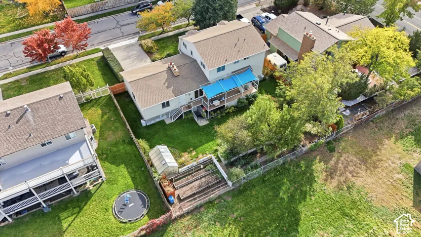Two-story residence featuring an elevated rear deck, fenced backyard, exterior greenhouse, and built-in raised garden beds