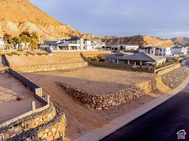 Tiered residential lot featuring extensive stone retaining walls, paved street access, and mountain backdrop