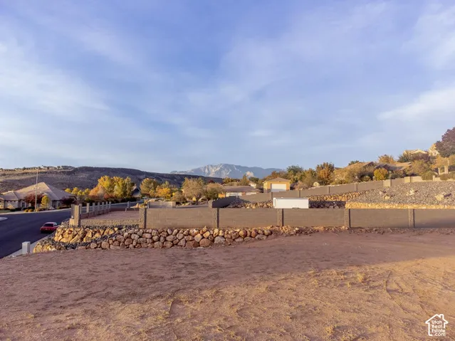 Elevated lot featuring stone retaining walls, block perimeter fencing, and mountain scenery