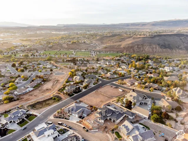 Aerial perspective featuring sprawling desert landscape, distant mountain range backdrop, and established suburban neighborhood grid
