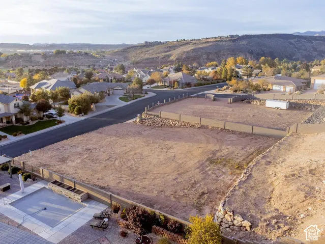 Residential lot featuring tiered boulder retaining walls, perimeter fencing, a concrete paver patio, and an inground swimming pool with a stone water feature