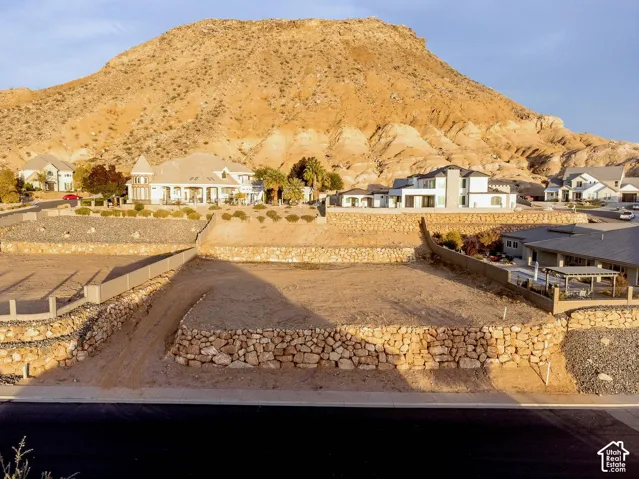 Tiered building lot featuring native rock retaining walls, asphalt street frontage, and mountain backdrop