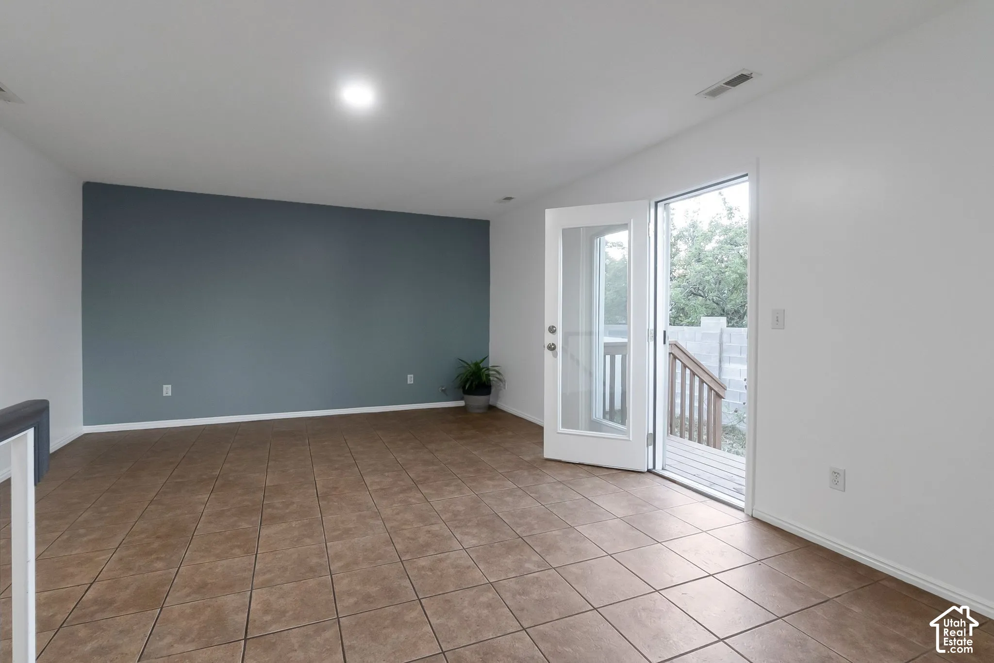 Interior space featuring neutral-toned tile flooring, a blue accent wall, and a full-light glass entry door