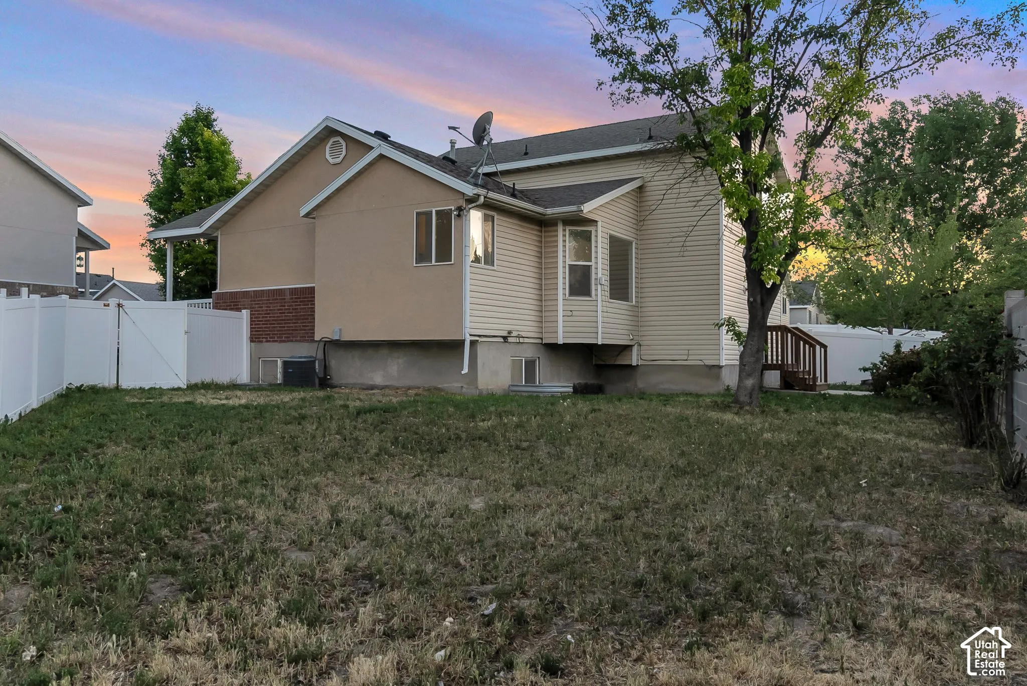 Exterior featuring vinyl siding, brick accents, a wood-constructed deck, and a white vinyl privacy fence