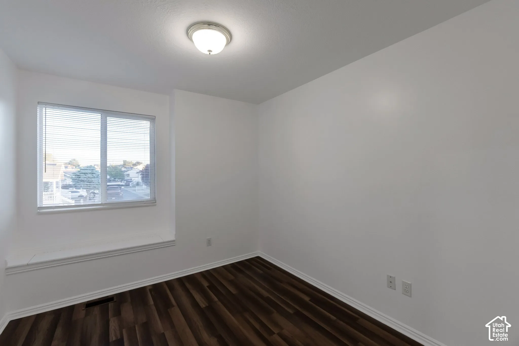 Room featuring wood-finish flooring, a built-in window seat, large multi-pane window, and a ceiling-mounted light fixture