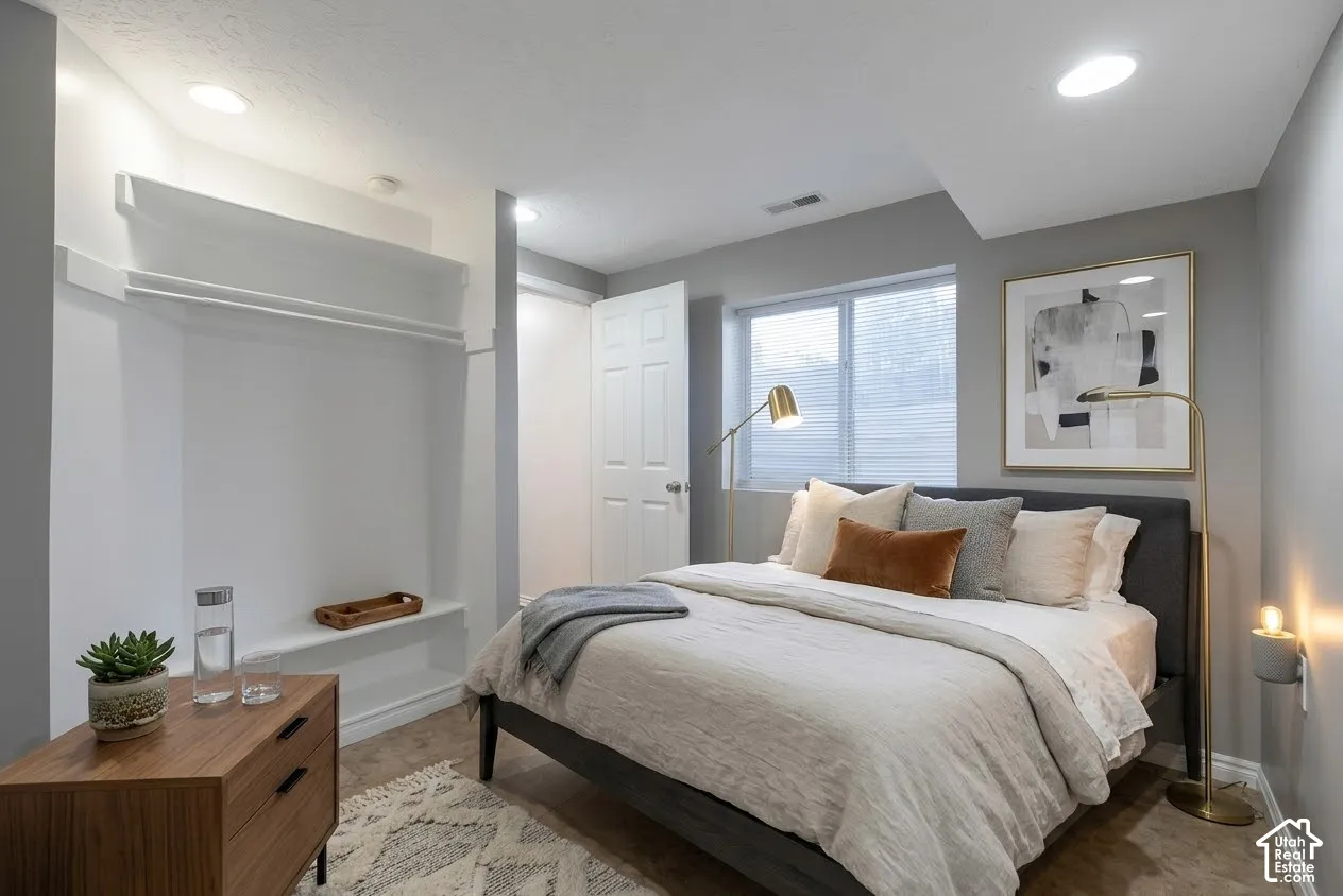 Neutral-toned room featuring recessed lighting, a built-in recessed shelf and clothing rod, and a window with horizontal blinds