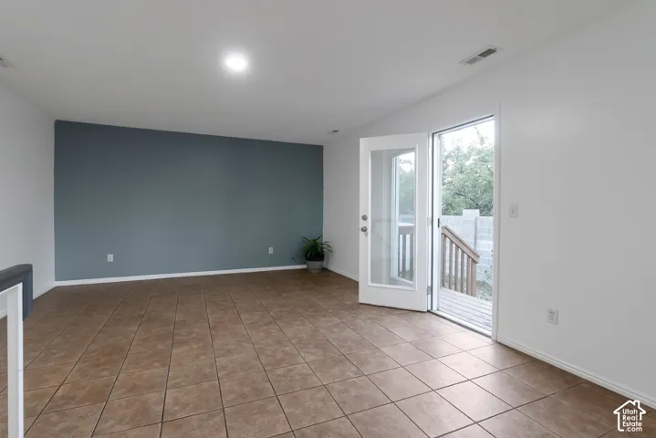 Interior space featuring neutral-toned tile flooring, a blue accent wall, and a full-light glass entry door
