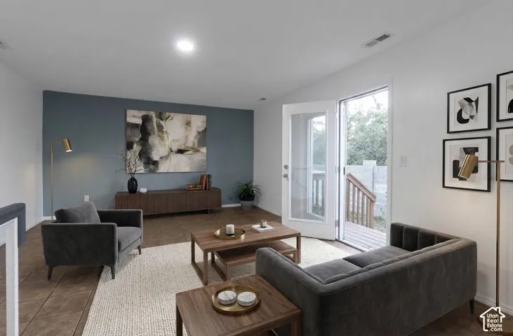 Living space featuring a contrasting accent wall, tile flooring, recessed lighting, and a glass-paned door providing exterior access