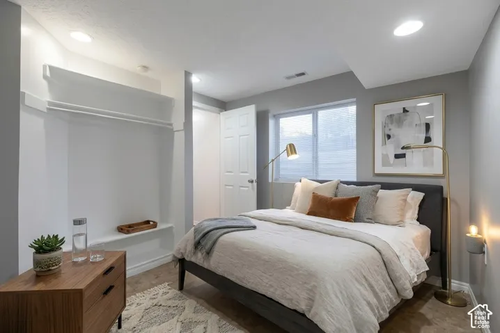 Neutral-toned room featuring recessed lighting, a built-in recessed shelf and clothing rod, and a window with horizontal blinds