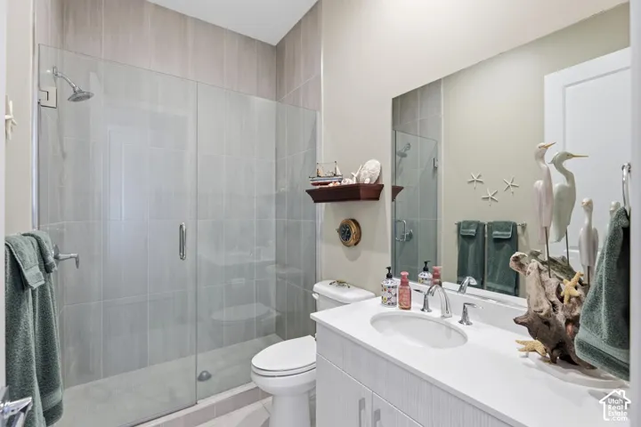 Bathroom featuring a glass-enclosed shower with floor-to-ceiling tile, vanity with integrated sink and countertop, and large wall-mounted mirror