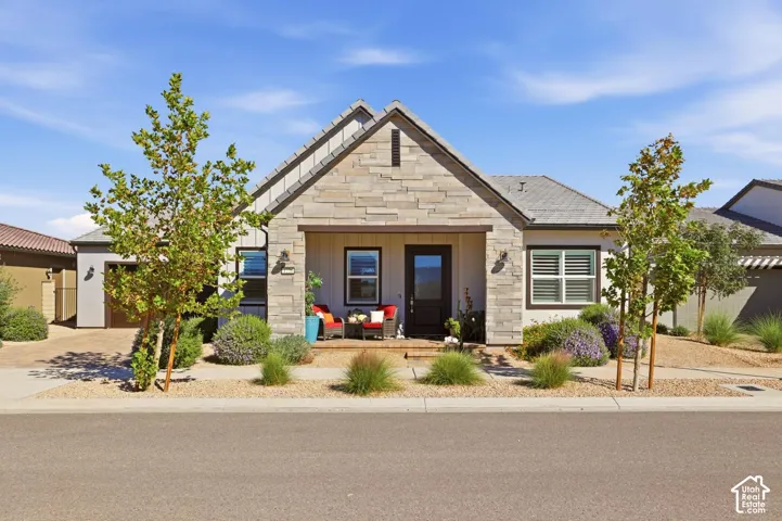 Single-story exterior featuring stacked stone siding, vertical board-and-batten siding, a covered entryway, and a concrete driveway