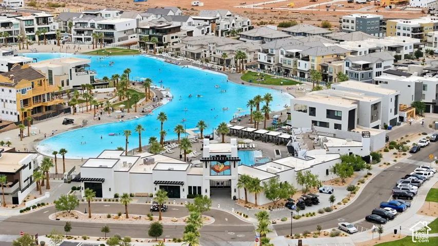 Large-scale recreational lagoon featuring sand-beach entry, palm-lined landscaping, and a central community clubhouse