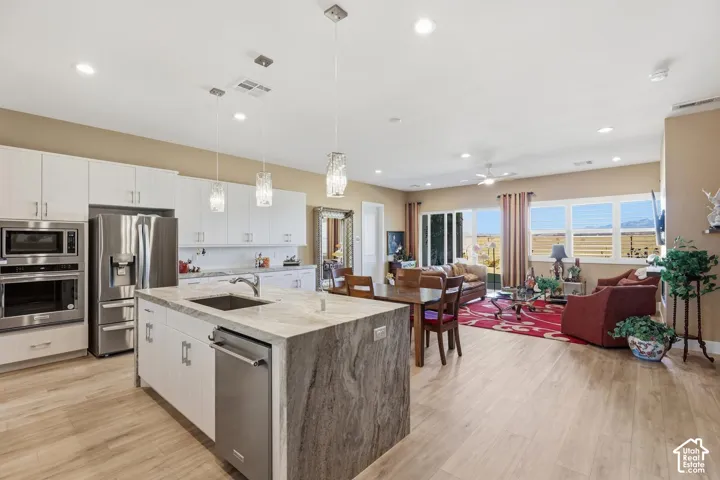 Kitchen featuring white cabinetry, an island with stone-finish countertops, stainless steel appliances, recessed lighting, and wood-finish flooring