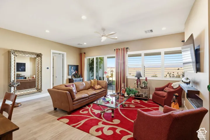 Living area featuring wood-finish flooring, recessed lighting, ceiling fan, sliding glass door, and horizontal window treatments