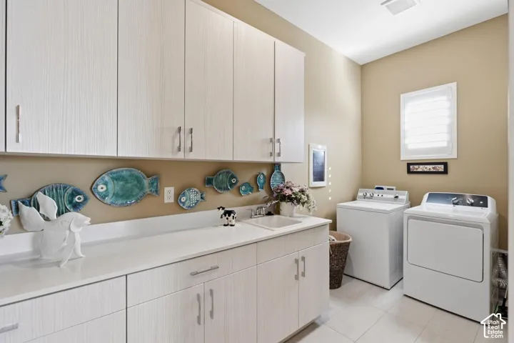 Laundry room featuring light wood-finish cabinetry, solid surface countertops, an integrated utility sink, and plantation shutters