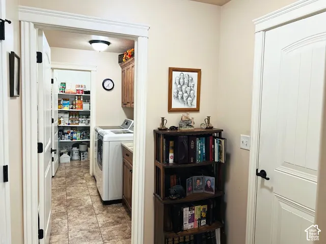 Utility room featuring tile flooring, wood cabinetry, and a walk-in pantry with built-in shelving