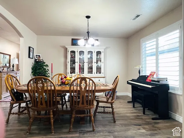 Dining area featuring wood-finish flooring, a built-in white glass-front china cabinet, multi-light chandelier, and large windows with interior shutters