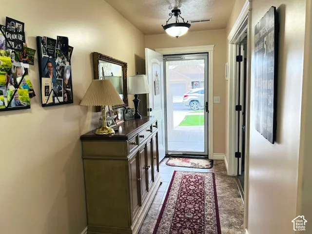 Entryway featuring a semi-flush mount light fixture, multi-panel exterior door with a screen, and stone-finish flooring