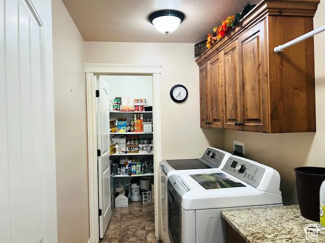 Utility room featuring wood-finish cabinetry, stone-patterned countertop, tile flooring, and a walk-in storage area with built-in shelving