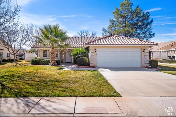 Single-story exterior featuring a tile roof, light-toned masonry facade, concrete driveway, and attached two-car garage